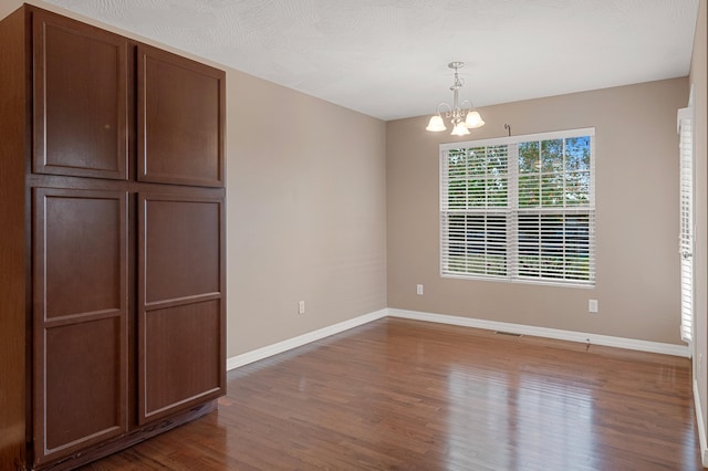 unfurnished dining area with hardwood / wood-style floors and a chandelier