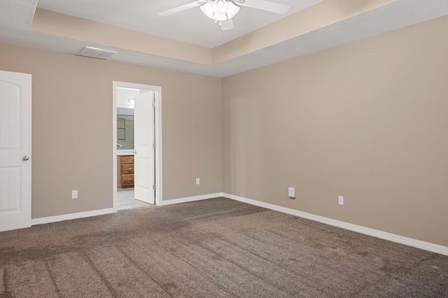 empty room with ceiling fan, a raised ceiling, and carpet