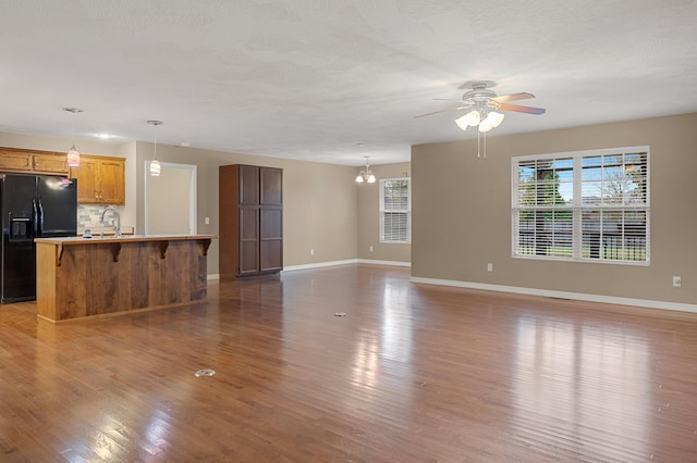 unfurnished living room featuring sink, dark hardwood / wood-style floors, and ceiling fan with notable chandelier