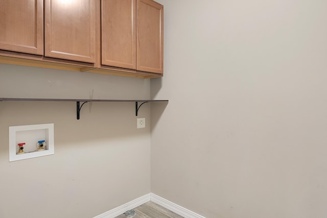 washroom with washer hookup, hardwood / wood-style flooring, and cabinets