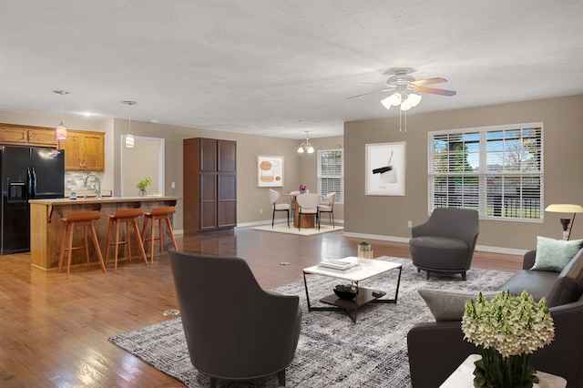 living room with sink, ceiling fan with notable chandelier, and dark hardwood / wood-style flooring