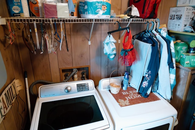 clothes washing area featuring wooden walls and washing machine and clothes dryer