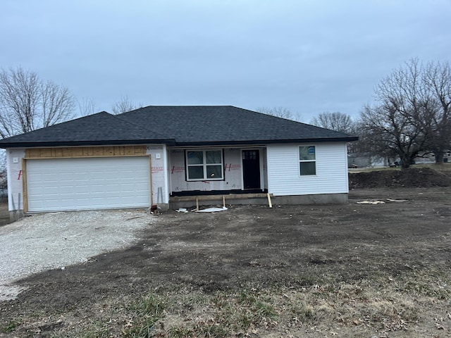 view of front of property with an attached garage, driveway, and roof with shingles