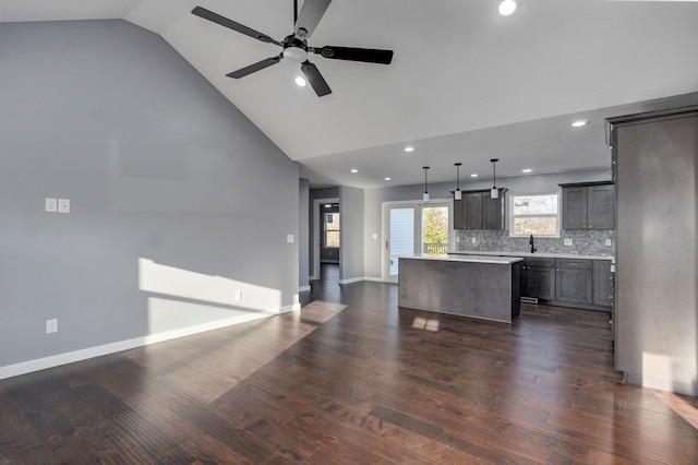 kitchen featuring tasteful backsplash, a kitchen island, open floor plan, light countertops, and dark wood-style floors