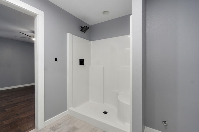 bathroom featuring baseboards, walk in shower, and wood finished floors