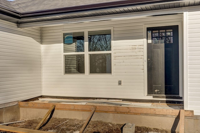 doorway to property featuring roof with shingles