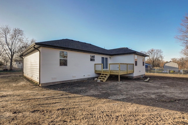 rear view of property featuring a wooden deck, roof with shingles, and fence