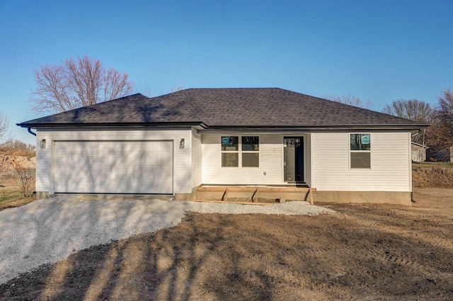 single story home with an attached garage, a shingled roof, and driveway