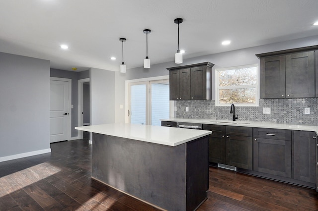 kitchen with a center island, light countertops, decorative backsplash, dark wood-style floors, and a sink