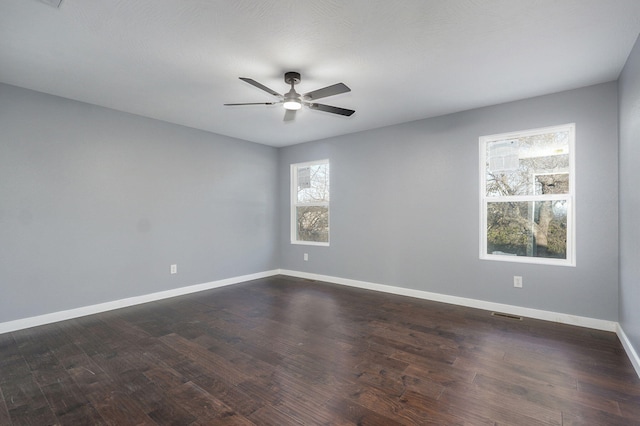 empty room featuring baseboards, dark wood-type flooring, and a ceiling fan