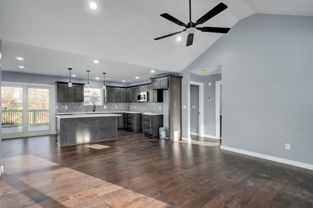 kitchen with stainless steel microwave, a center island, dark wood-type flooring, light countertops, and a sink