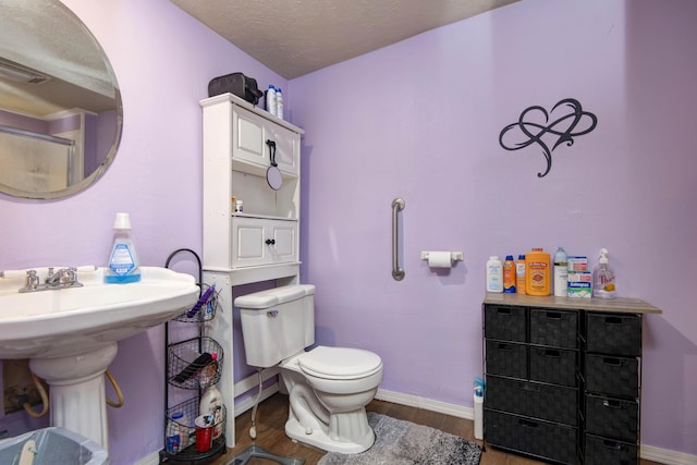 bathroom featuring sink, hardwood / wood-style flooring, toilet, and a textured ceiling