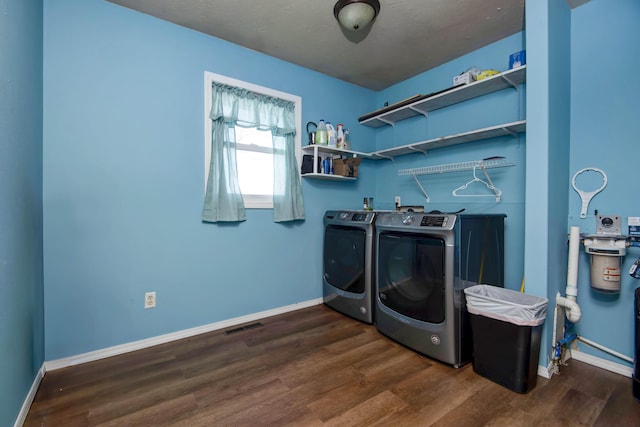 clothes washing area with dark wood-type flooring and separate washer and dryer