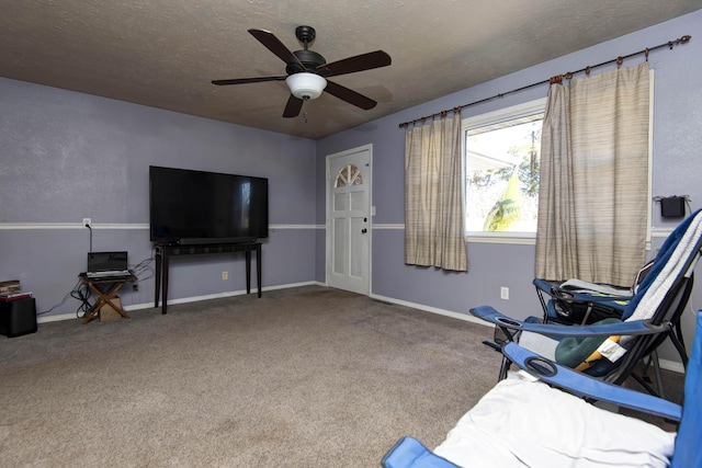 sitting room featuring ceiling fan, carpet, and a textured ceiling