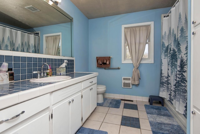 bathroom with heating unit, backsplash, tile patterned flooring, vanity, and toilet