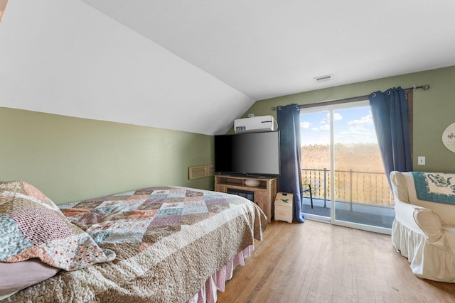 bedroom with lofted ceiling, access to exterior, and light hardwood / wood-style floors