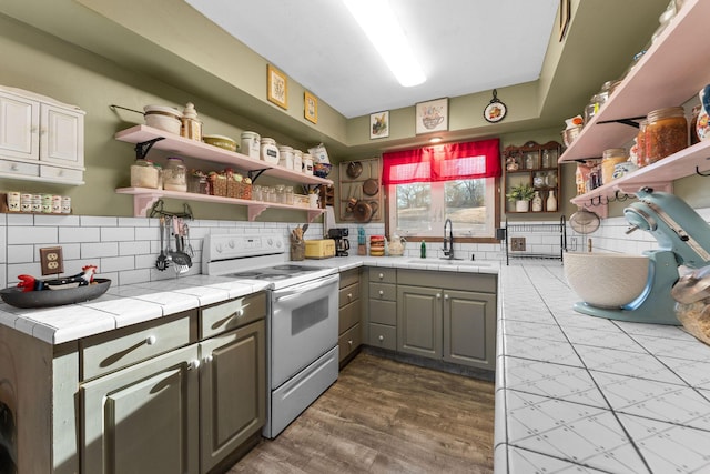 kitchen featuring sink, decorative backsplash, tile counters, and white range with electric stovetop