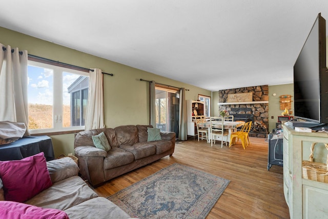 living room with a stone fireplace and light hardwood / wood-style floors