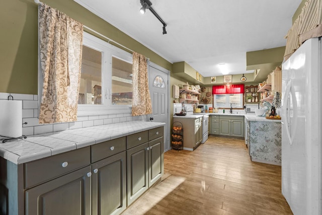 kitchen featuring sink, tile countertops, light hardwood / wood-style flooring, kitchen peninsula, and white appliances