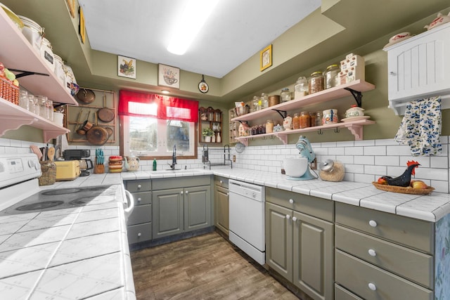 kitchen with sink, tile counters, white appliances, and decorative backsplash