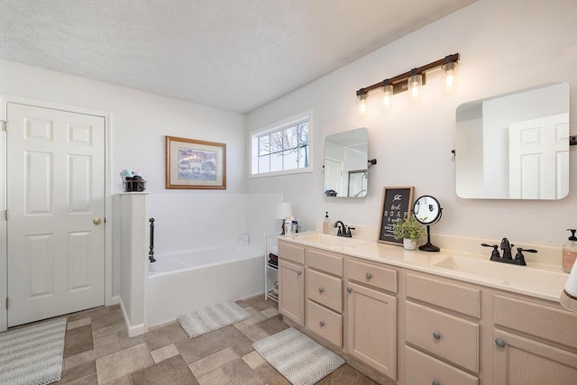 bathroom featuring vanity, a bath, and a textured ceiling