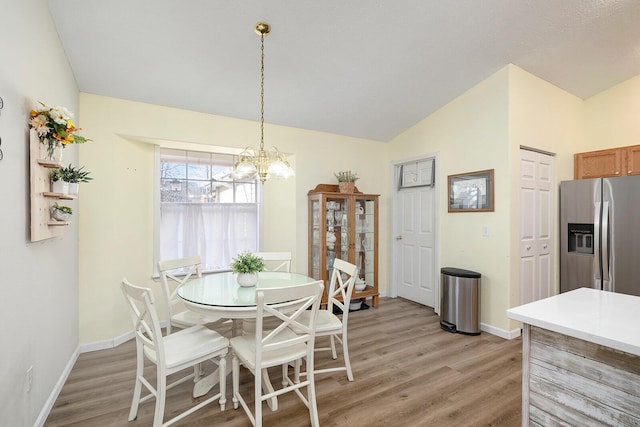 dining area featuring lofted ceiling, a notable chandelier, and light hardwood / wood-style flooring