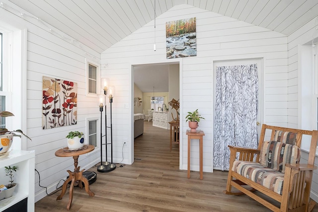 hallway with vaulted ceiling, wood-type flooring, and wooden walls