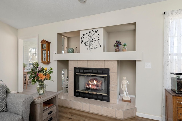 living room with hardwood / wood-style floors, plenty of natural light, a tile fireplace, and a textured ceiling