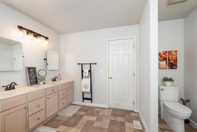 bathroom featuring vanity, a textured ceiling, and toilet