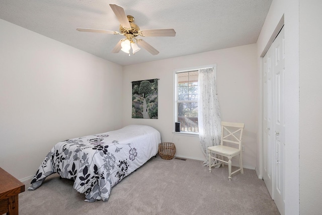 bedroom featuring ceiling fan, light colored carpet, a closet, and a textured ceiling