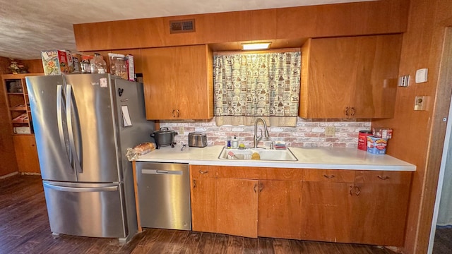 kitchen featuring stainless steel appliances, sink, dark wood-type flooring, and backsplash