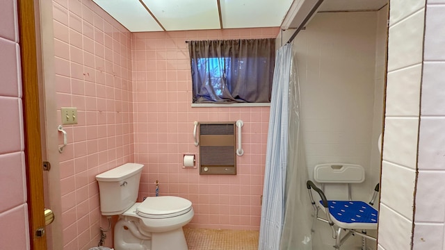 bathroom featuring tile patterned floors, toilet, heating unit, and tile walls