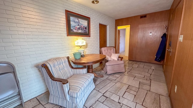 living area featuring wooden walls and brick wall