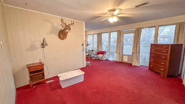 misc room with ceiling fan, plenty of natural light, carpet flooring, and wood walls