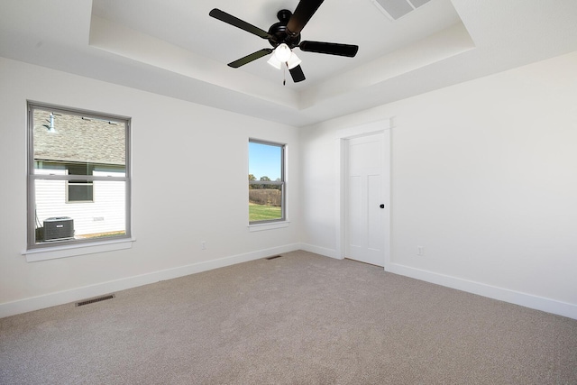 carpeted empty room with a raised ceiling and ceiling fan