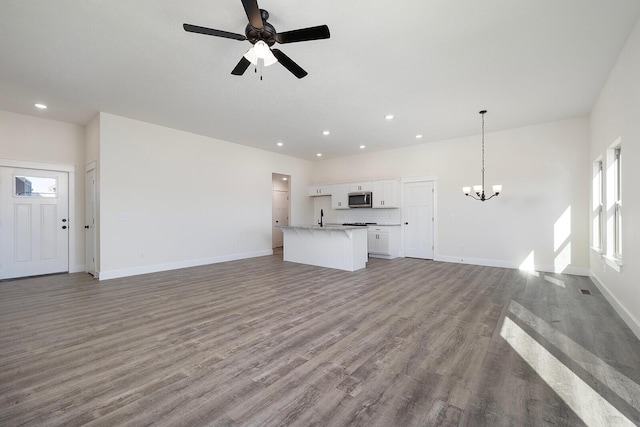 unfurnished living room featuring sink, ceiling fan with notable chandelier, and light wood-type flooring