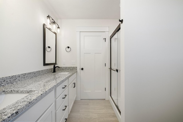 bathroom with hardwood / wood-style flooring, vanity, and a shower with door