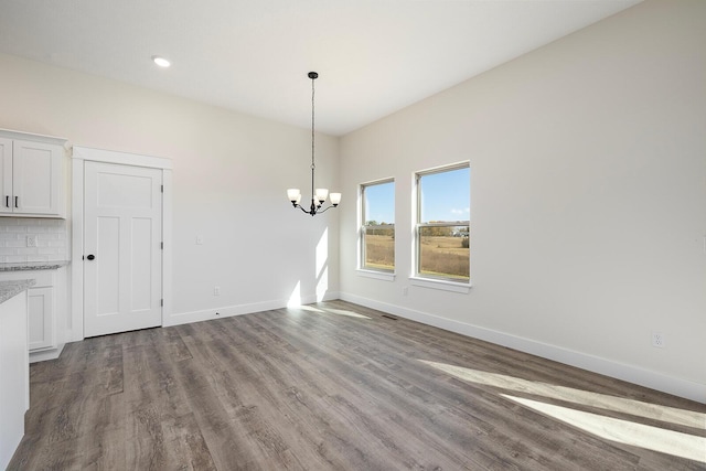 unfurnished dining area with hardwood / wood-style floors and a notable chandelier