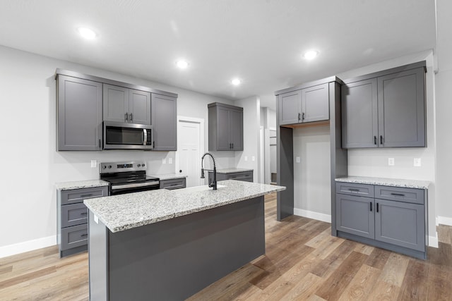 kitchen featuring appliances with stainless steel finishes, a center island with sink, and gray cabinetry