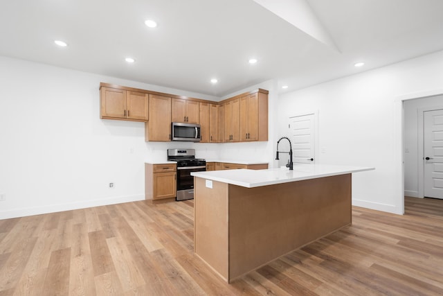 kitchen featuring vaulted ceiling, appliances with stainless steel finishes, a kitchen island with sink, and light wood-type flooring