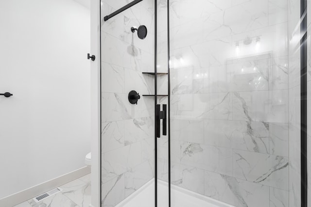 bathroom featuring a shower with shower door and toilet