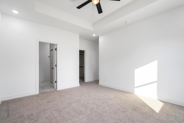 unfurnished room with light colored carpet, a raised ceiling, and ceiling fan