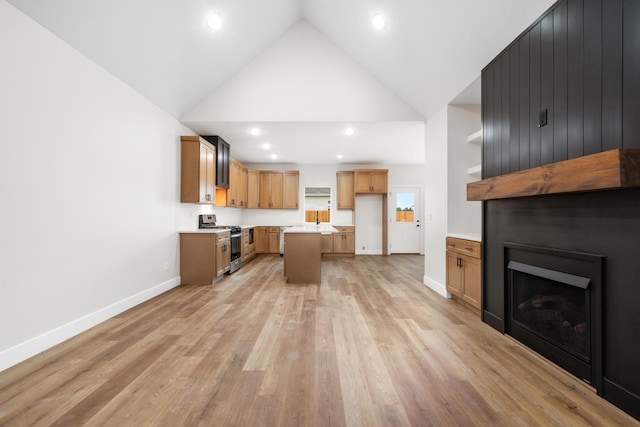 kitchen with light wood-type flooring, a fireplace, high vaulted ceiling, a kitchen island, and stainless steel gas stove