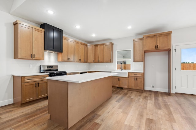 kitchen with sink, gas range, a center island, and light hardwood / wood-style floors