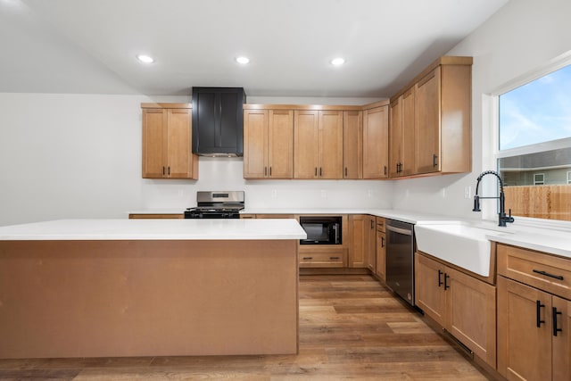 kitchen featuring appliances with stainless steel finishes, sink, a center island, and hardwood / wood-style floors