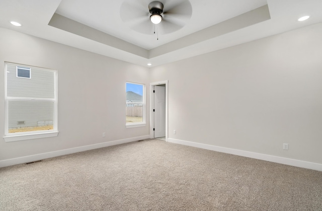 spare room featuring carpet, a tray ceiling, and ceiling fan