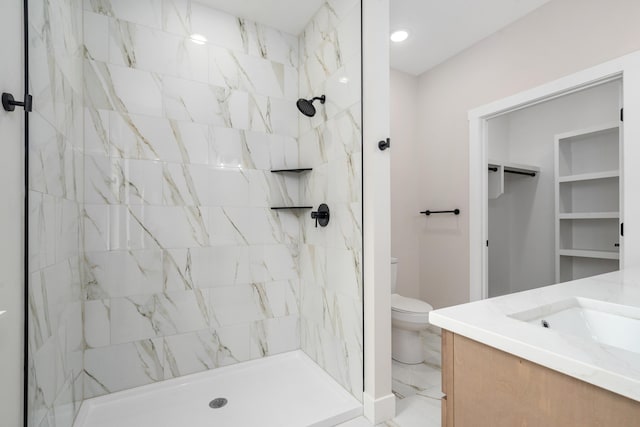 bathroom with vanity, tiled shower, and toilet