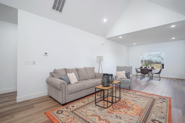 living area featuring baseboards, visible vents, high vaulted ceiling, and wood finished floors