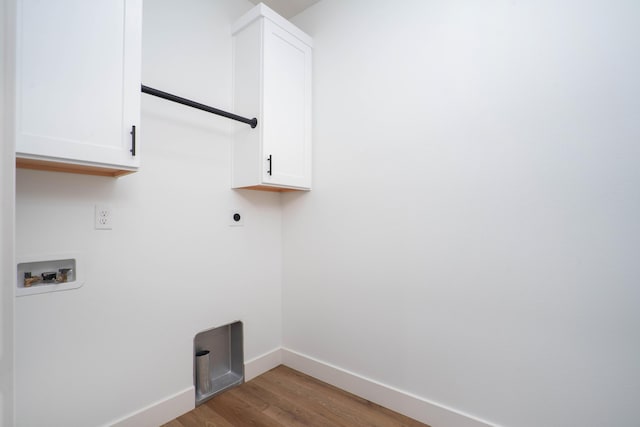 clothes washing area with hookup for a washing machine, baseboards, wood finished floors, electric dryer hookup, and cabinet space