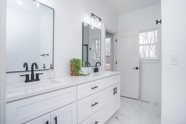 full bathroom with baseboards, marble finish floor, a sink, and double vanity